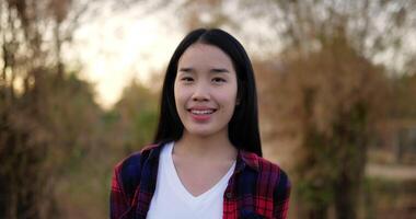 Portrait of an Asian young happy farmer woman looking at camera and smiling with a farmland background. Agriculture farming concept. Slow motion. video