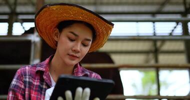 Nahaufnahme, asiatische attraktive landwirtschaftliche Viehzüchterin verwendet digitalen Stift, um auf dem Tablet zu schreiben, während sie Tiere auf dem Bauernhof überprüft video