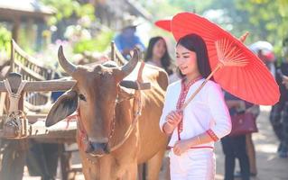 mujer asiática con vestido típico tailandés con paraguas rojo, traje tailandés foto