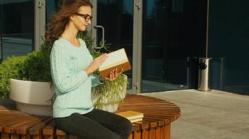 Charming young brunette student reading a book in the street video