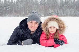 familia feliz de papá y niño disfrutan de un día nevado de invierno foto