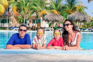 familia joven con dos niños disfruta de las vacaciones de verano en la piscina al aire libre foto