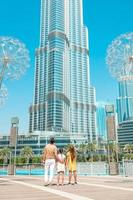 familia feliz caminando en dubai con el rascacielos burj khalifa en el fondo. foto