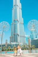 familia feliz caminando en dubai con el rascacielos burj khalifa en el fondo. foto