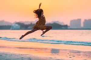 Adorable happy little girl on white beach at sunset. photo