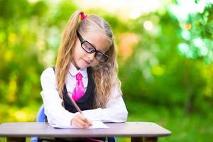 Cute little schoolgirl with notes and pencils going back to school outdoor photo