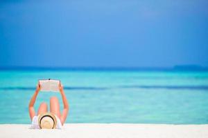 Happy girl reading during tropical white beach photo