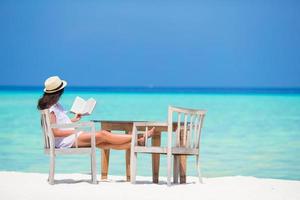 Young woman reading at outdoor beach cafe photo