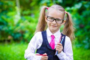 Little happy girl with pencils going back to school outdoor photo