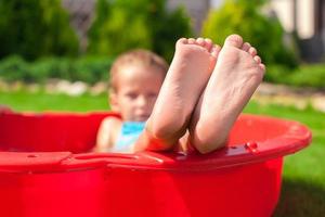 primer plano de las piernas de un niño pequeño en una pequeña piscina roja foto