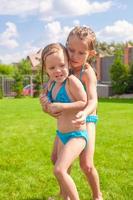 dos hermanitas jugando y chapoteando en la piscina en un día caluroso y soleado foto