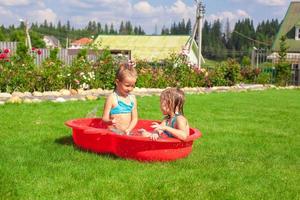 Two little sisters playing and splashing in the pool on a hot sunny day photo
