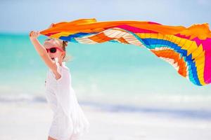 Happy little girl having fun running with pareo on tropical white beach photo