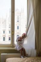 adorable niña mirando por la ventana al duomo, milán, italia foto