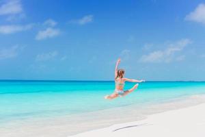 Active little girl at beach having a lot of fun on the shore making a leap photo