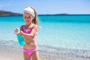 Little adorable girl in swimsuit with suntan lotion bottle photo