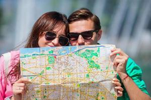 jóvenes amigos turistas que viajan de vacaciones en europa sonriendo felices. primer plano familia caucásica con mapa de la ciudad en busca de atracciones foto