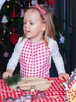 adorable niña con rodillo horneando galletas de jengibre para navidad foto