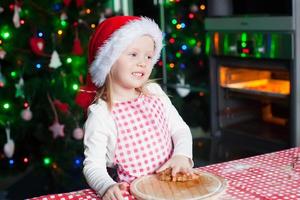 Happy cute little girl in the kitchen baking gingerbread photo