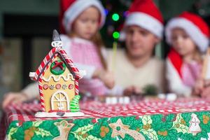 Gingerbread fairy house decorated by colorful candies on a background of happy family photo