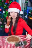 Young woman in Christmas hat baking gingerbread at home photo