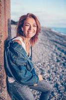 retrato de moda al aire libre de una chica elegante con chaqueta de jeans en la playa. foto