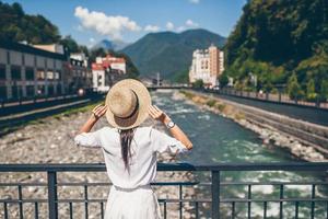 chica feliz con sombrero en el terraplén de un río de montaña en una ciudad europea. foto