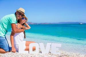 Young beautiful family sitting on the beach with word Love photo