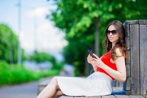 Beautiful girl listening music by smartphone on summer holidays. Young attractive tourist with mobile phone outdoors enjoying holidays. photo