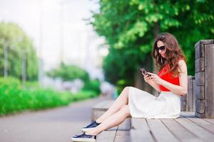 Beautiful girl listening music by smartphone on summer holidays. Young attractive tourist with mobile phone outdoors enjoying holidays. photo