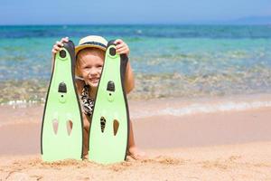 Little girl with flippers and goggles for snorkling on the beach photo