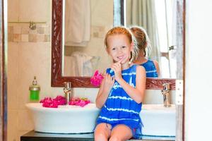 niña cepillándose los dientes en el baño foto