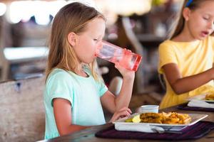 Adorable little girl having lunch in outdoor cafe photo