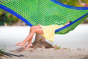 Adorable little girl on tropical vacation relaxing in hammock photo