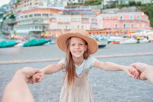 Adorable little girl on warm and sunny summer day in Positano town in Italy photo