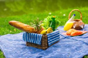 Picnic basket with fruits, bread and bottle of white wine photo