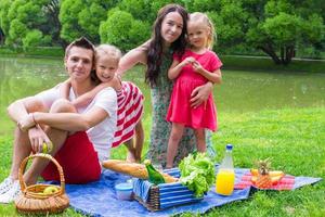 Happy parents and two kids picnicking outdoors photo