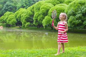 Adorable little girl playing badminton on picnic photo