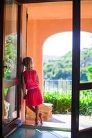 Adorable little girl on the balcony in exotic resort at summer vacatiom photo