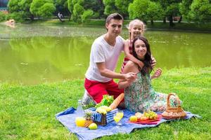 Happy young family picnicking outdoors near the lake photo