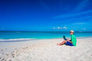 Young man with tablet computer and cell phone on tropical beach photo