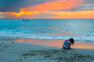 Silhouette of adorable little girl on the beach at sunset photo