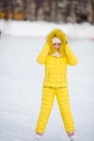 Adorable little girl skating on the ice rink outdoors photo