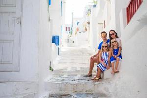 vacaciones familiares en europa. padres e hijos en la calle del típico pueblo tradicional griego en la isla de mykonos, en grecia foto
