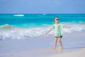 Cute little girl walking at beach during caribbean vacation photo