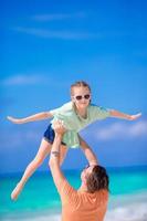 Little girl and happy dad having fun during beach vacation photo