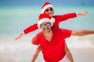 Father and daughter in Santa Hat have fun at tropical beach photo