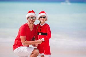 Father and daughter in Santa Hat have fun at tropical beach photo