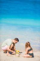 Family making sand castle at tropical white beach. Father and girl playing with sand on tropical beach photo