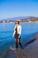 Beautiful young woman walking on the beach in winter sunny day alone photo
